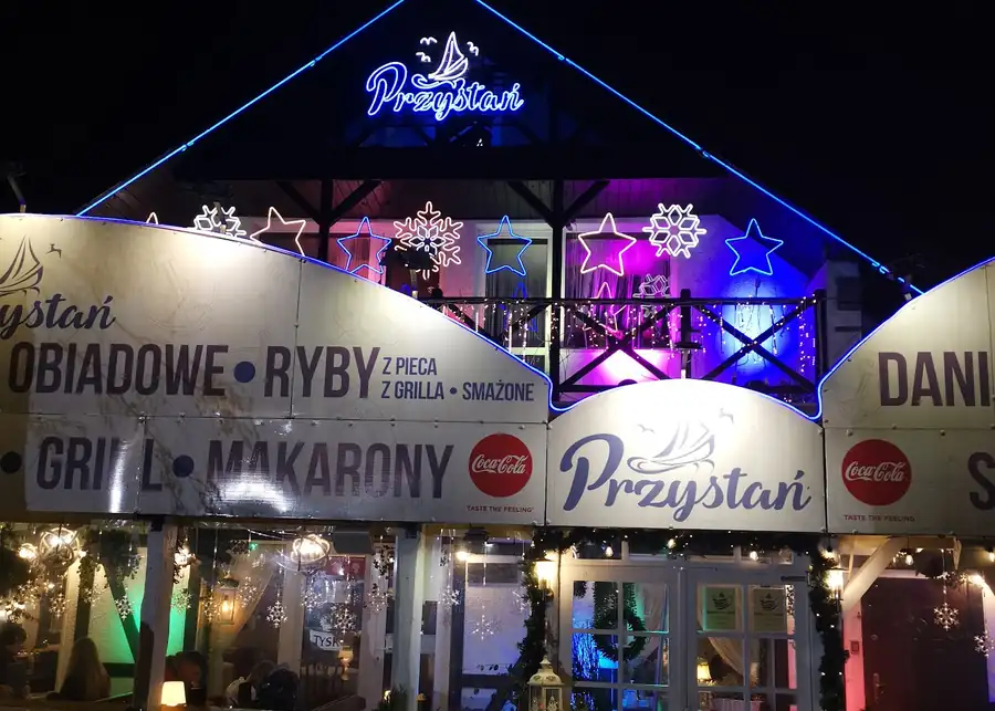 Podświetlony wieczorem budynek z szyldem Przystań